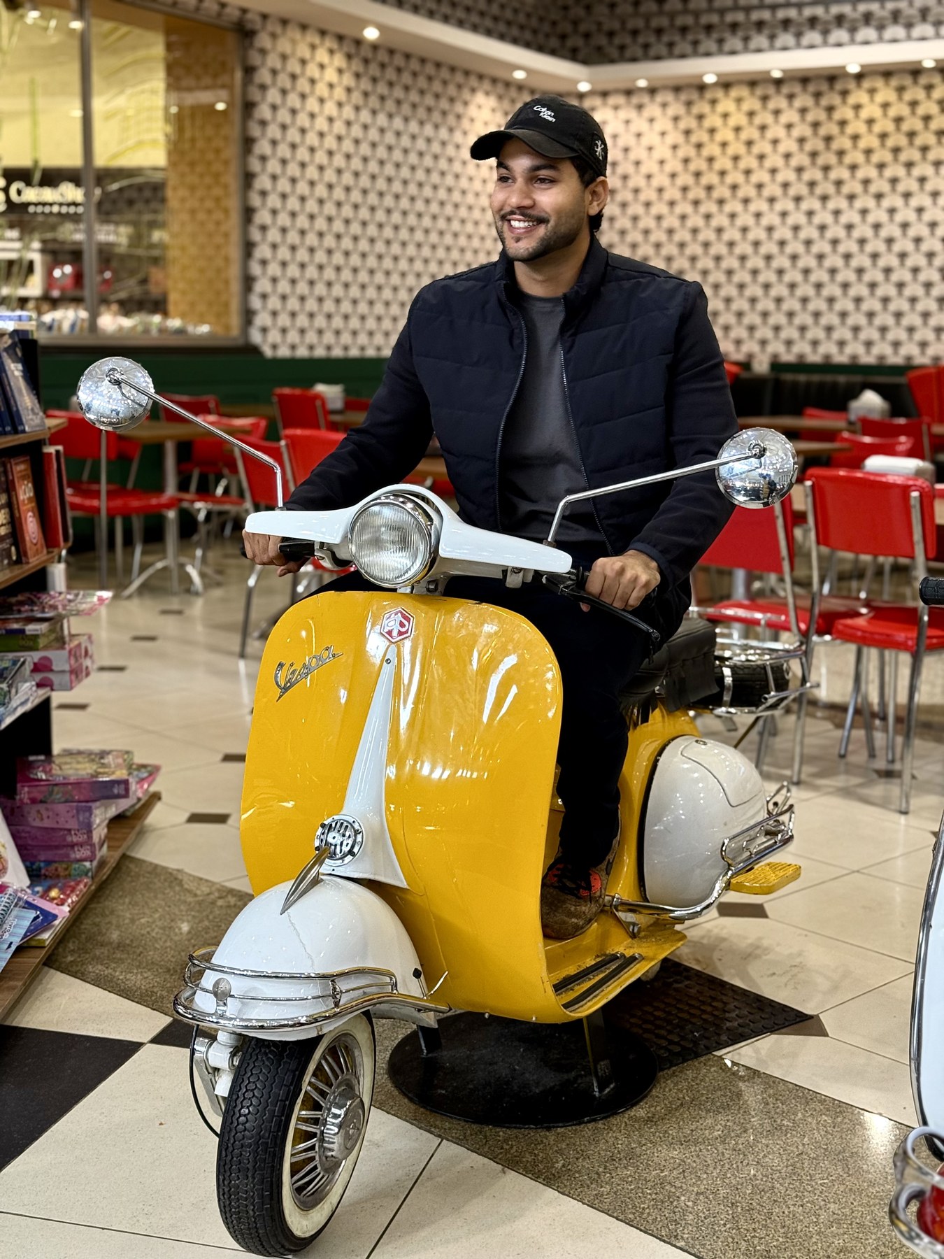 Aiko Saback sentado em uma scooter amarela